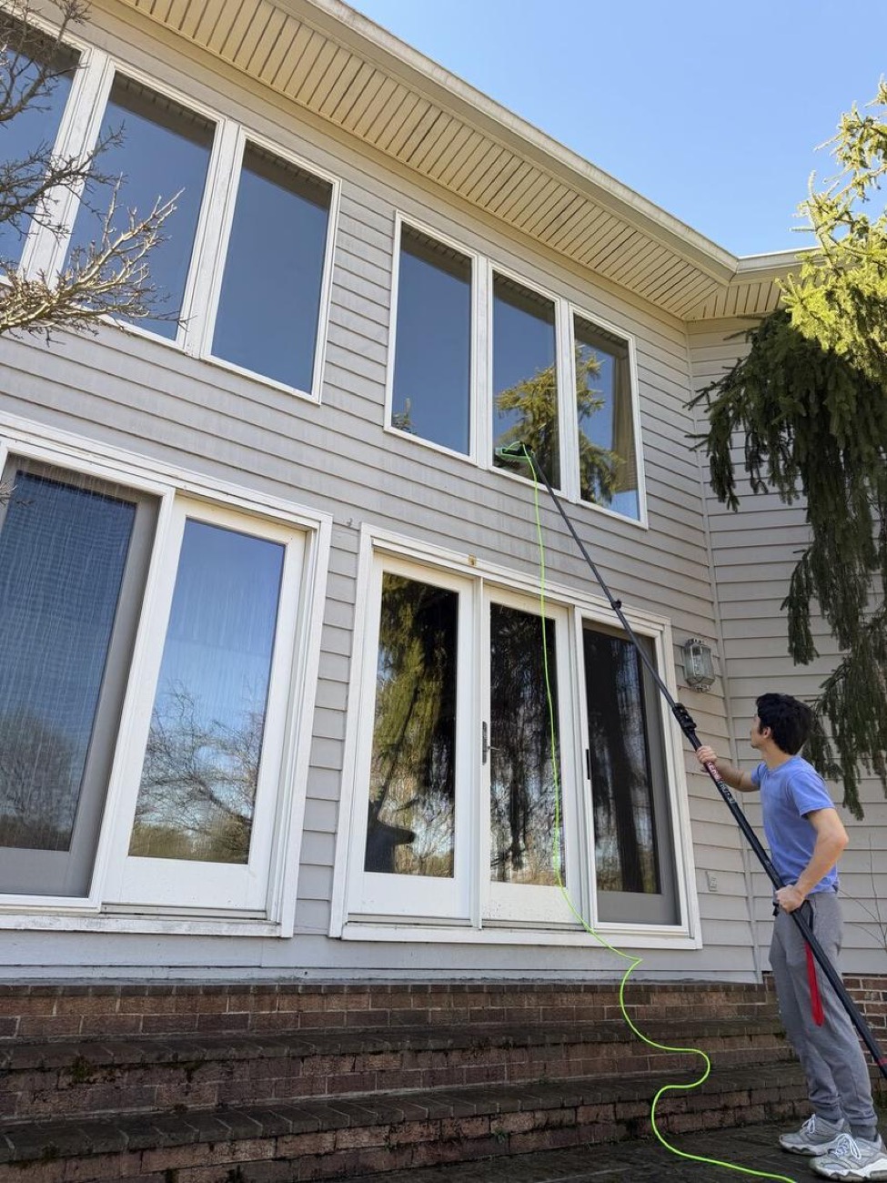 A Rejuvenate technician cleaning windows on a bright Maryland day